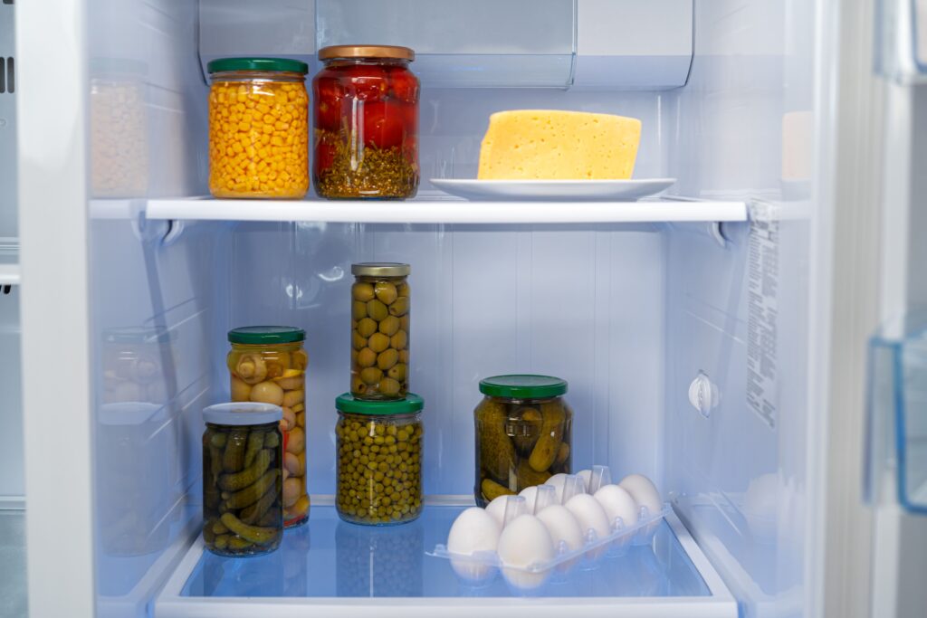 glass jars of canned products on a fridge shelf utc