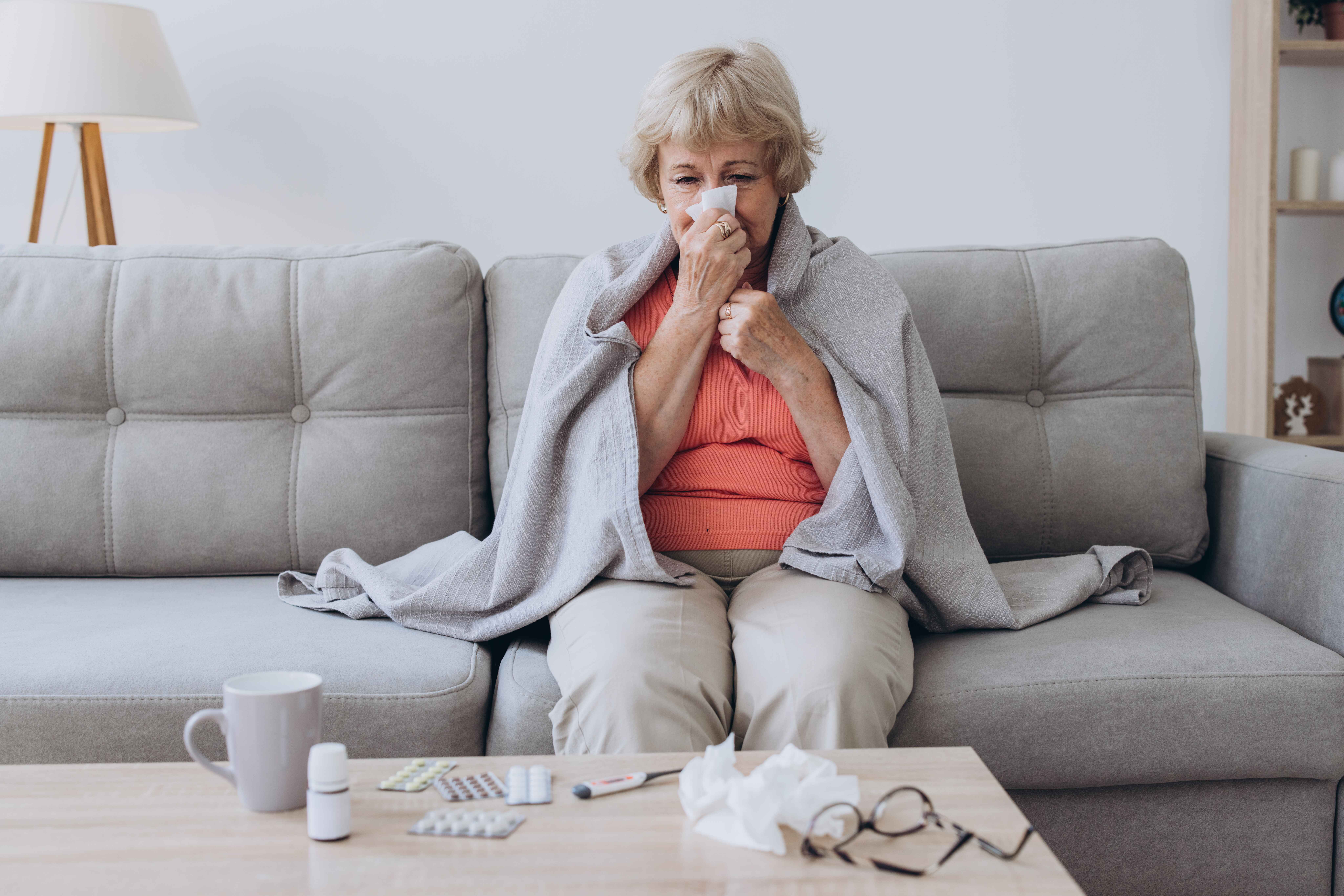senior woman being sick having flu sitting on sofa