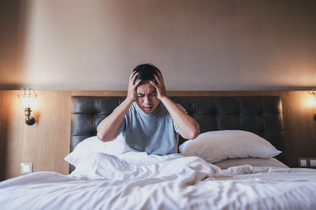 man-headache-or-migraine-on-bed-min