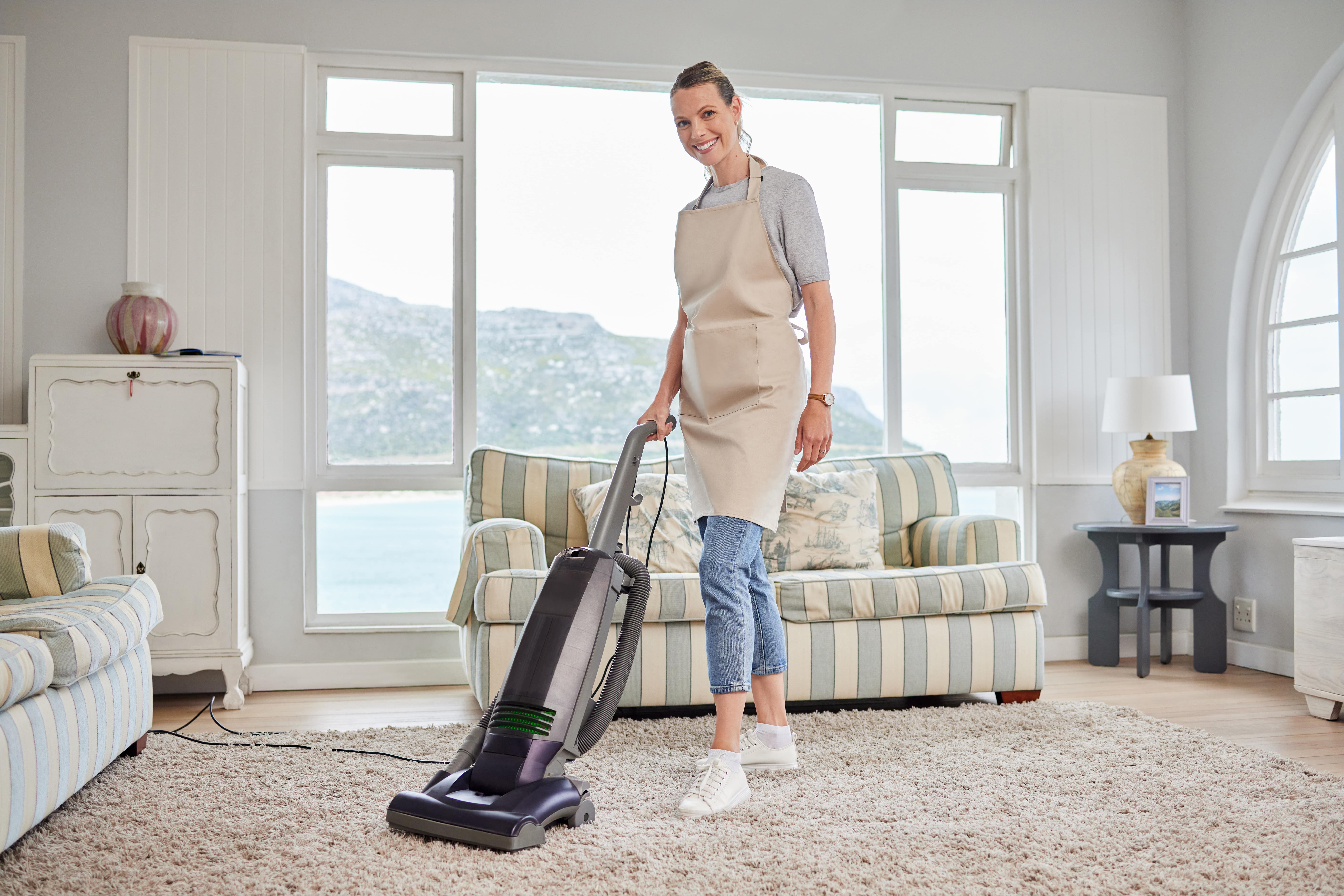 portrait-of-a-young-woman-vacuuming-a-carpet-in-th-min