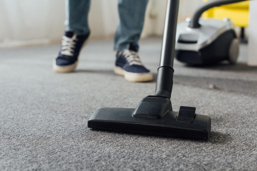 cropped-view-of-man-cleaning-carpet-with-vacuum